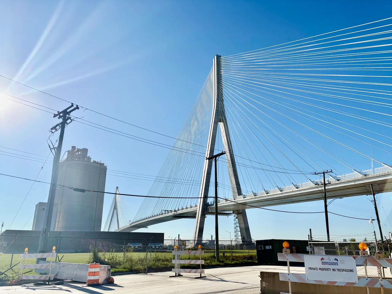 A tall bridge tower and white cable stays against a blue sky in Detroit.