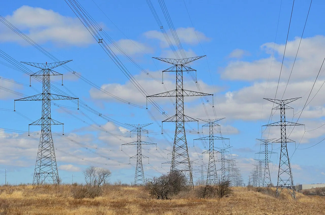 Steel transmission towers and power lines beneath a blue sky in Markham, Ontario.
